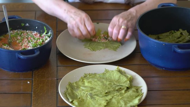 Turkish woman making Sarma - Traditional Turkish food. Grape leaves stuffed with rice and minced meat.