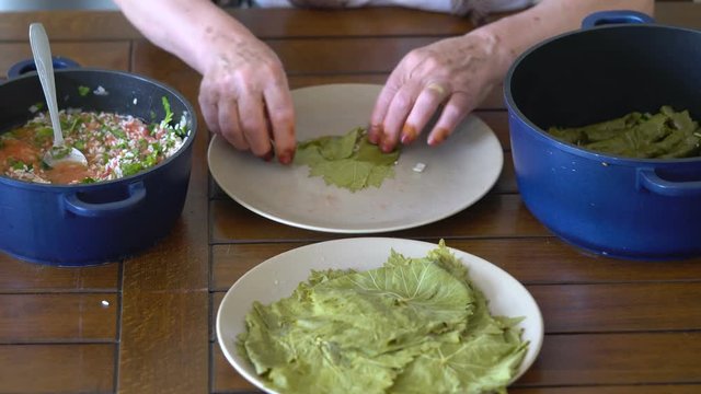 Turkish woman making Sarma - Traditional Turkish food. Grape leaves stuffed with rice and minced meat.