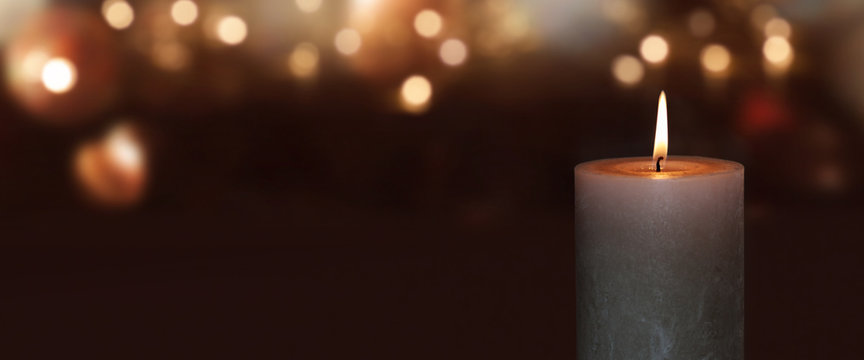 Burning candle with golden bokeh