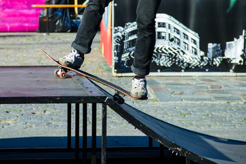 Skateboarder legs riding skateboard at skatepark