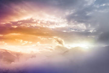 Bright saturated colors dawn with clouds and fog over the top of the Nepal mountains. Fabulously beautiful panoramic view, illuminated by the golden rays of the rising sun. Nature landscape background