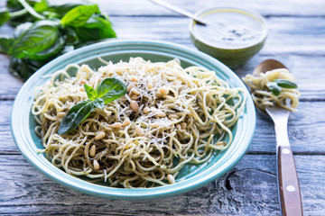 pasta spaghetti with homemade pesto sauce and basil leafs, wood background