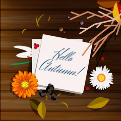 Autumn greeting card, background, backdrop. A note with Hello Autumn! lettering on a wooden table with beautiful flowers (Chammomile, marigold), berries and leaves