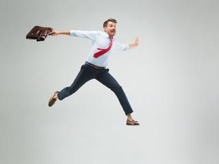 Businessman running with a briefcase, isolated on gray background