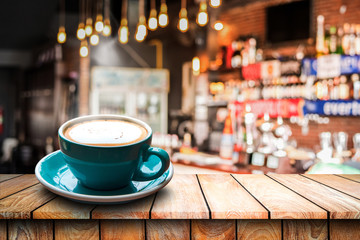 Cup of coffee and smoke on wooden desk table in Blurred cafe background.
