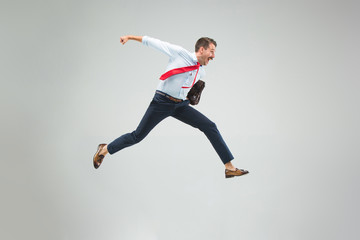Businessman running with a briefcase, isolated on gray background