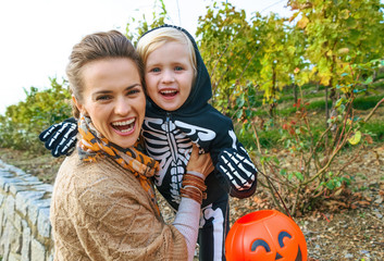 Obraz premium smiling modern mother and daughter on Halloween outdoors