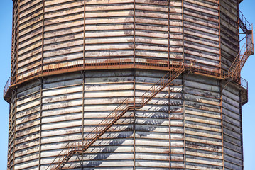 Concrete cylindrical industrial silo with metal stairs with safety railing and large bore pipes.