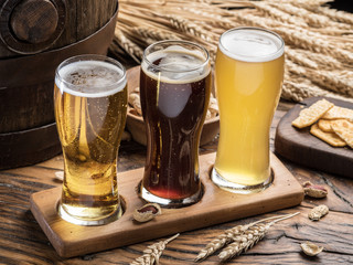 Glasses of beer and snacks on the wooden table.