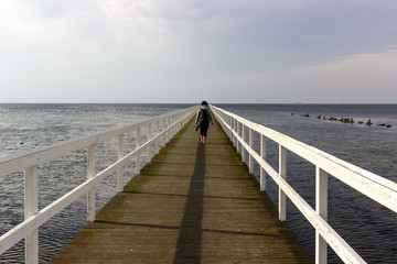 Giovane donna cammina sul molo