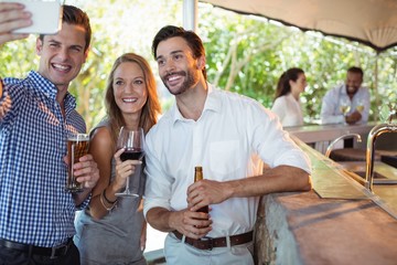 Friends taking selfie while having alcohol at counter