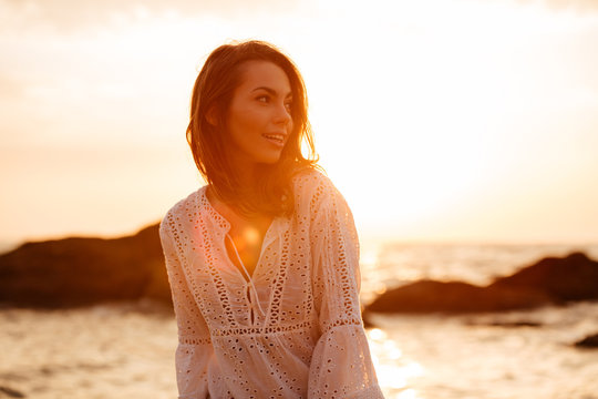 Beauty brunette woman in light summer dress posing on beach