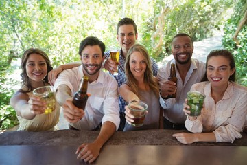 Portrait of smiling friends showing alcohol at counter