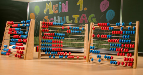 Rechenrahmen auf Schultisch vor Schultafel mit Schrift mein erster Schultag