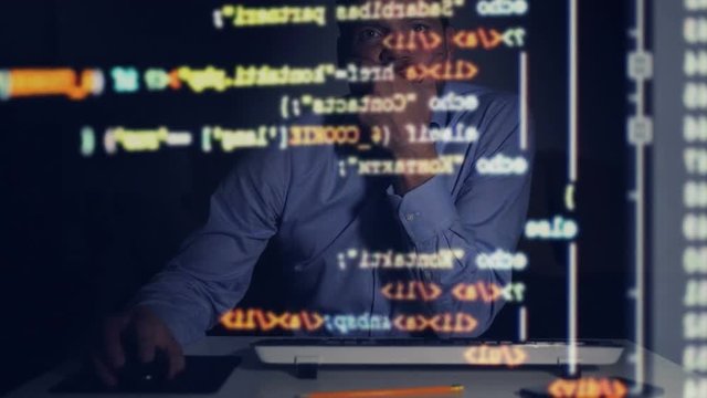 programmer scrolling down programming code on computer screen in dark room