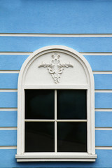 The facade of a beautiful structural building. Window in the form of an arch in the blue wall