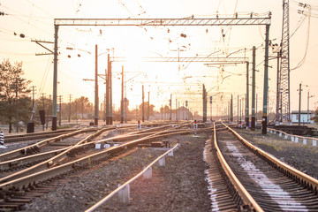 An empty railway sorting station or terminal with lots of junction, crossroads, semaphore showing red or green light, in a bright sunset light.