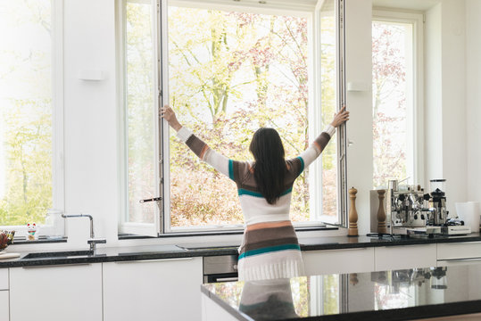 Woman in kitchen opening the window