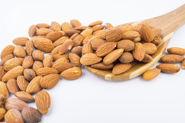 Almonds nuts in wooden ladle isolated on white background. Tasty medicine from nature.