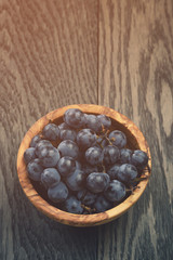 ripe isabella grapes in wood bowl on table