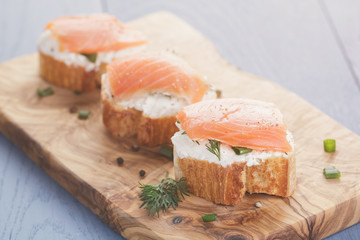 baguette slices with soft cheese and salmon on wood table