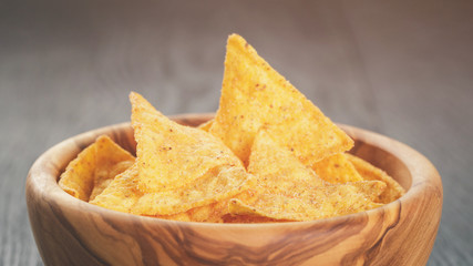 tortilla chips in olive wood bowl on wooden table