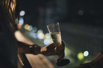 Gril with a glass of champagne with city lights background