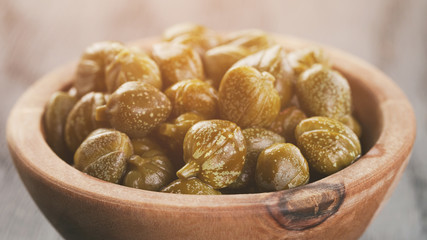 marinated capers in olive bowl on wood table