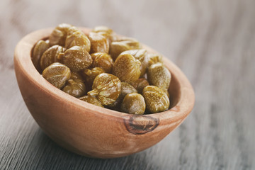 marinated capers in olive bowl on wood table