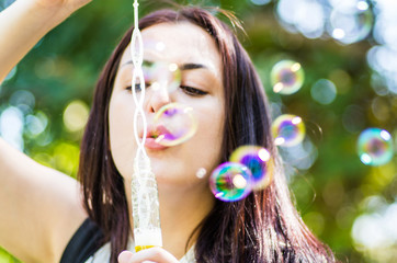 young woman blowing soap bubbles in the park