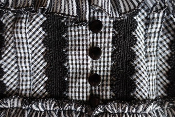 Close view of detail of clothing with black lace and buttons