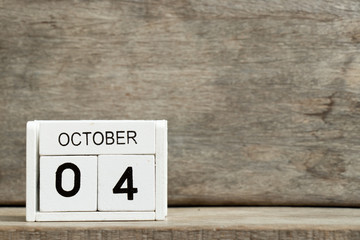 White block calendar present date 4 and month October on wood background