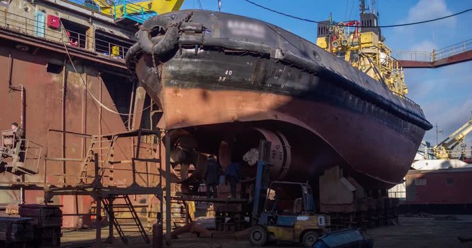 Workers repair old vessel at floating dock at the shipyard. Ship propeller reconstruction. Fishing boat welding timelapse 4k video.