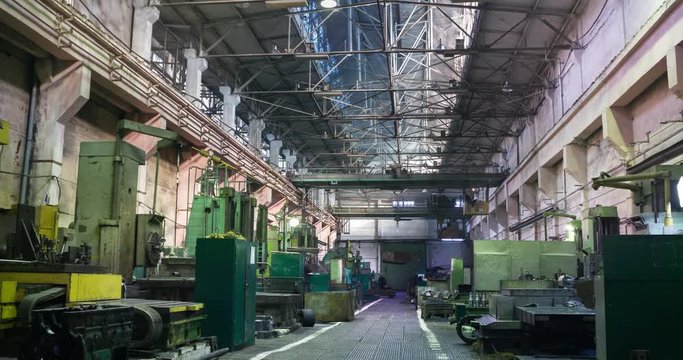Factory beam crane moves on top of a large workshop. Workers at turning lathes ding metal processing at plant and move cargo. 4k timelapse video