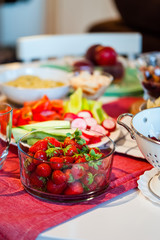 Healthy dinner party at home, served table with drinks, fruits and vegetable dishes and bowls. 