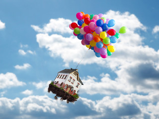 Balloons with house flies above the clouds. Concept