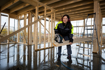 Happy Female Carpenter Cutting Wood With Electric Saw At Site