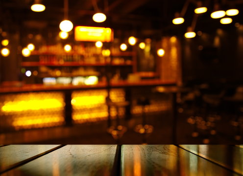 top of wood table with light reflection with abstract blur bar or club in the dark night background