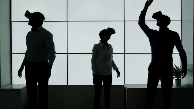  Business team in silhouette trying out virtual reality viewers on white background