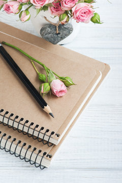 Workplace with notebooks and roses