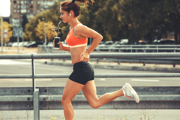 Female runner jogging on the city street by the traffic road.City environment.