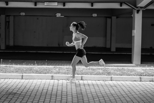 Female runner jogging on the city street under the overpass.City environment.