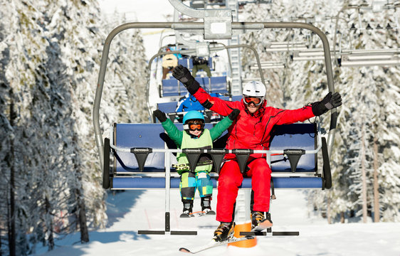 Ski instructor with little boy enjoying on ski lift