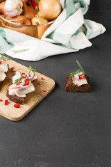 Sandwich with herring, black bread, black background, hot pepper, pickled onion, vertical, selective focus