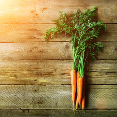 Bunch of fresh organic carrots on a wooden background with sunlights. Concept of diet, raw, vegetarian meal