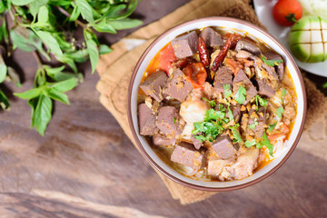 Thai Northern food (Kanom Jeen Nam Ngeaw) with vegetables on wooden background,spicy rice noodles soup,rice vermicelli served with curry