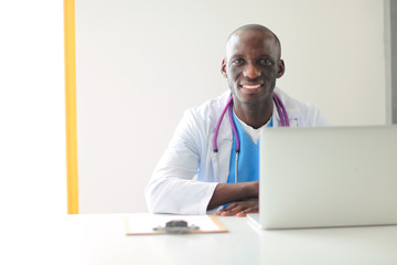 Portrait of young male doctor wearing headset while using computer at desk in clinic. Doctor.