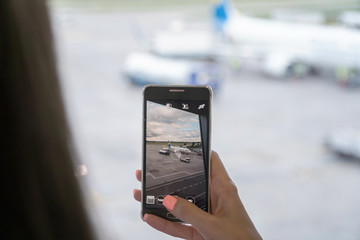 Close up of woman hands taking photo of plane. Travel Concept