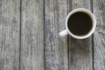 White cup of coffee on old, wooden table. High angle view