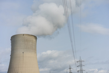 nuclear power plant chimney with condensation smoke on a cloudy day with power pole electricity...